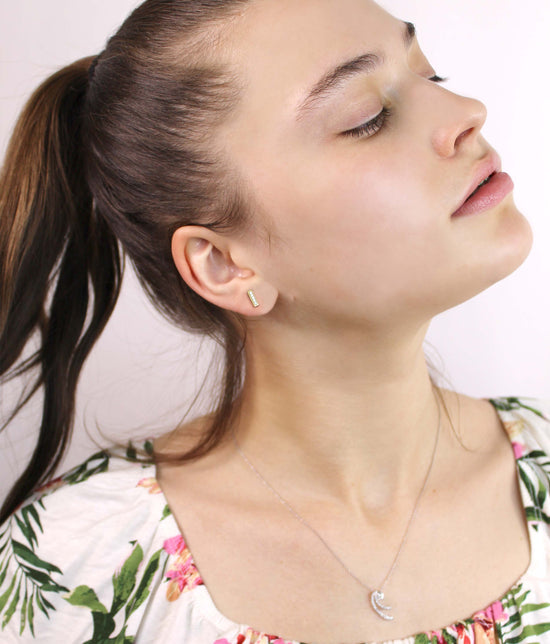 Close-up of a woman wearing gold earrings and a necklace with a white background